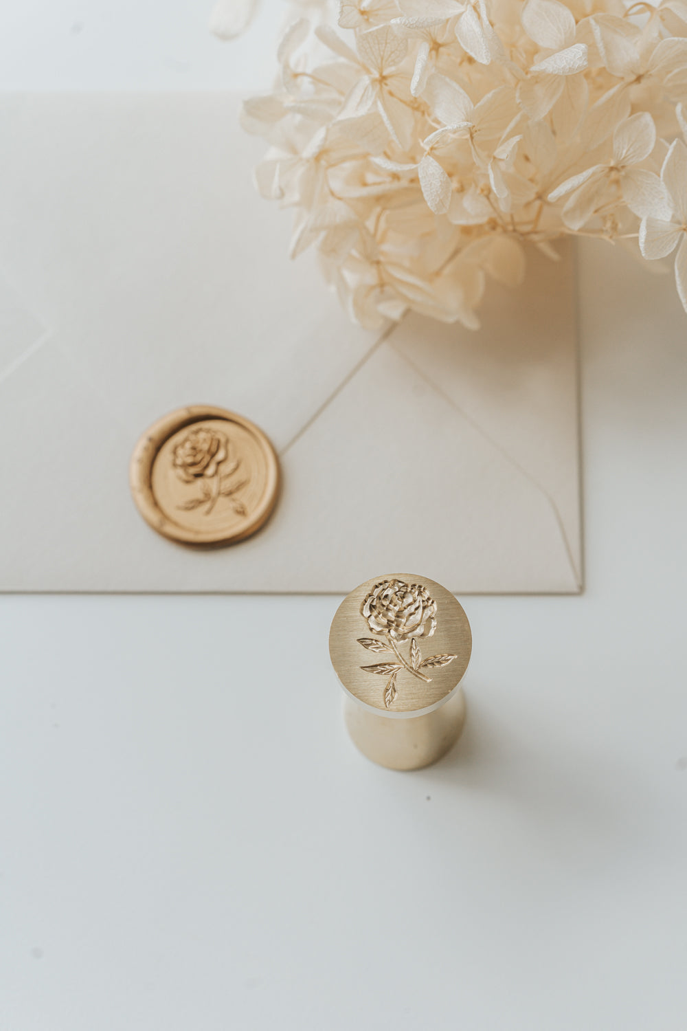 Peony wax seal stamp and gold sealing wax on envelope for wedding stationery and invitation suites