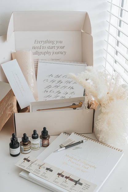 Beginner calligraphy supplies including ink, nibs, pen holder, and alphabet practice sheets