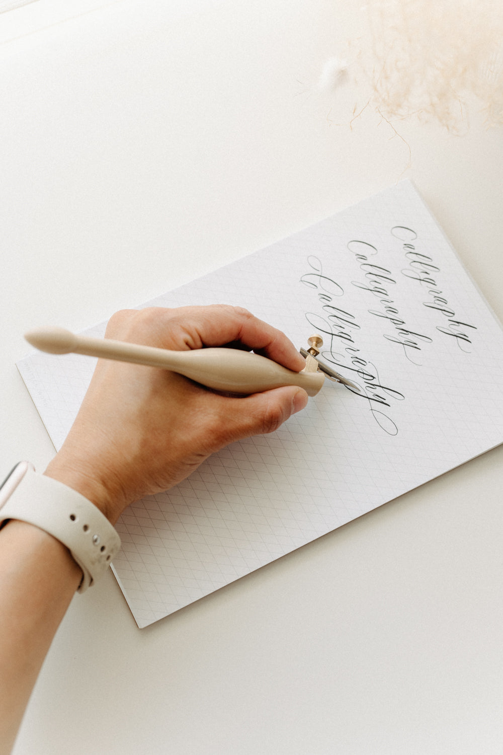 Left-handed modern calligraphy practice using a pointed pen and nib on guide sheets