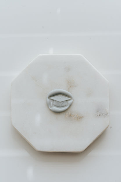 Graduation wax seal with cap design on white marble surface