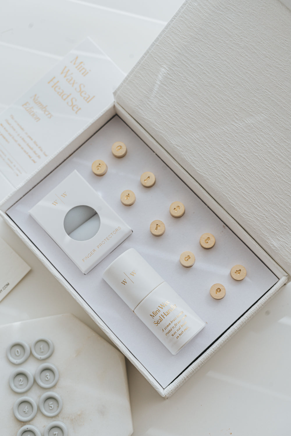 Open box showing mini wax seal number heads, handle, and finger protectors in premium packaging
