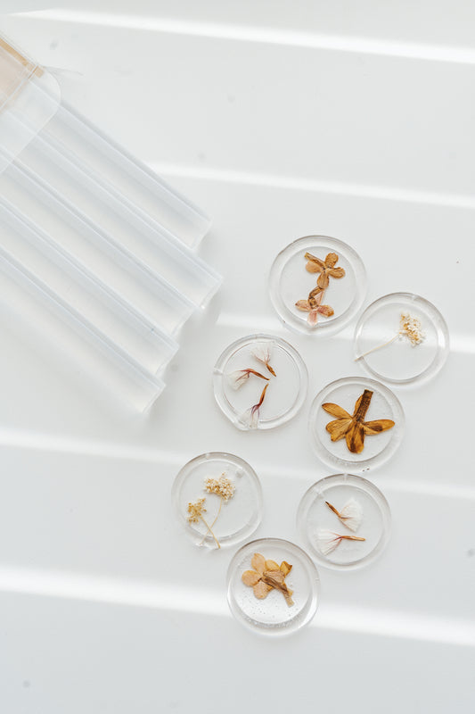 Clear wax seals with dried flowers beside translucent glue gun wax sticks