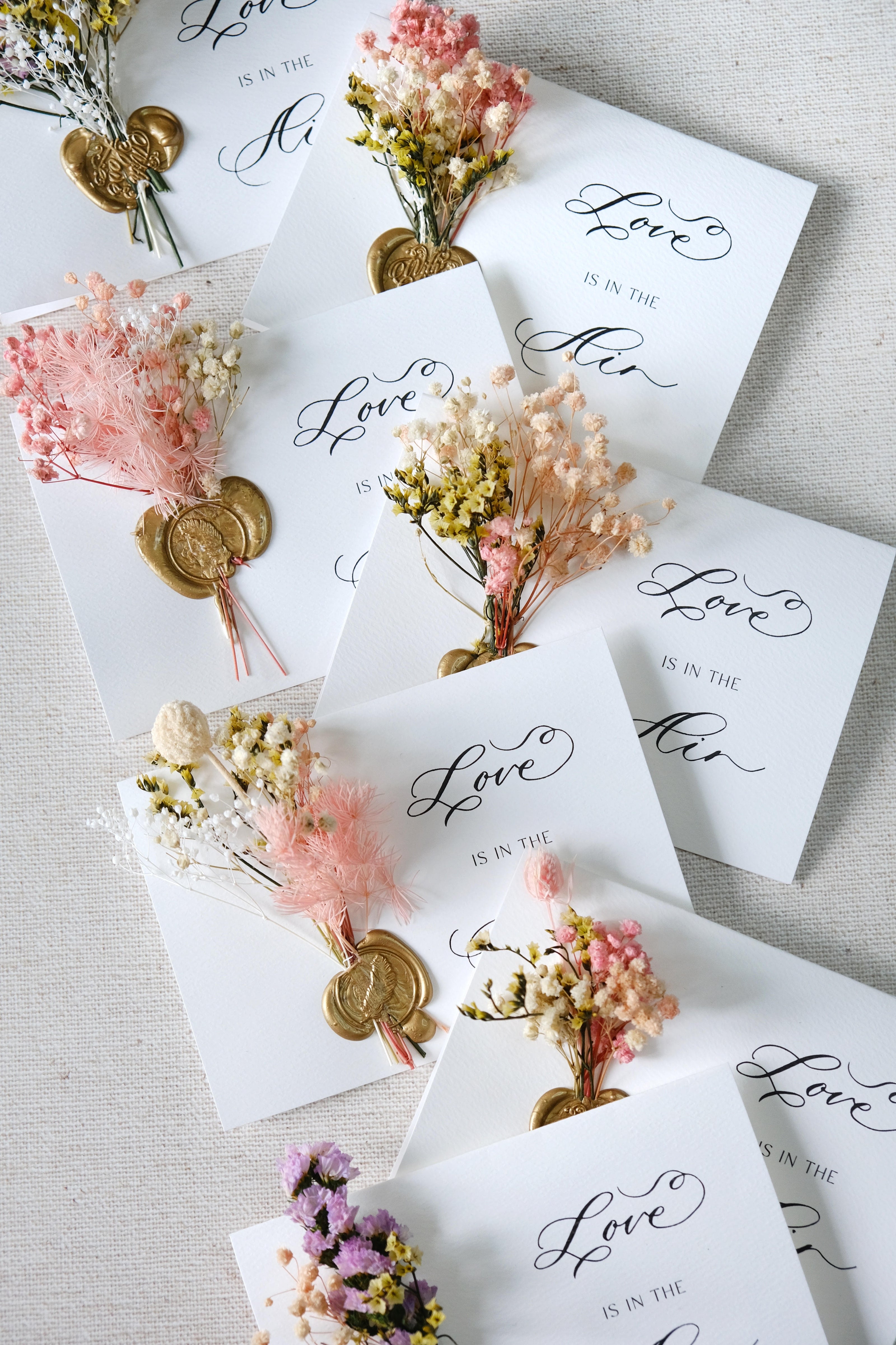 Wedding place cards with modern calligraphy, handmade wax seals, and dried floral arrangements for elegant event stationery.
