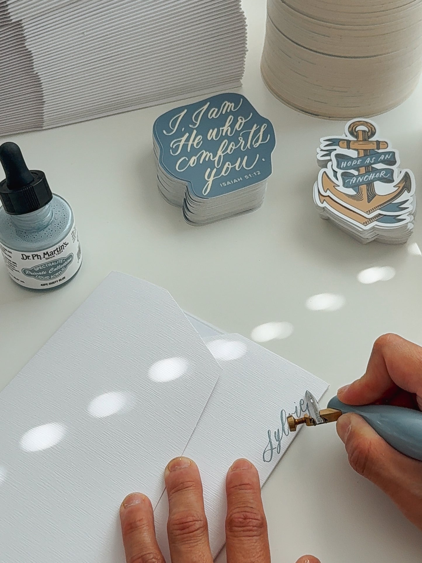 Hand lettering a name with dip pen and Dr. Ph. Martin's ink for Christian snail mail club, Isaiah 51:12 and anchor Scripture stickers in background