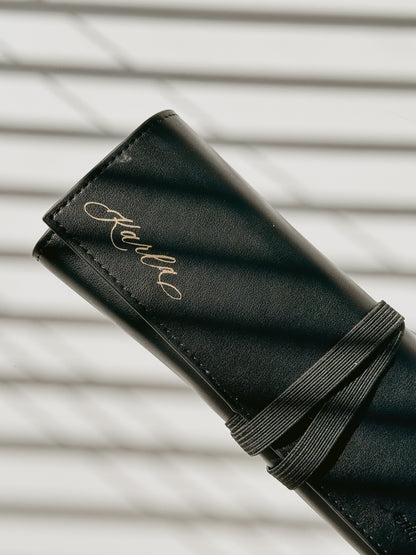Personalized black vegan leather pen roll featuring custom calligraphy name engraving and secure elastic closure, stylish organizer for calligraphy tools, pens, and art supplies.