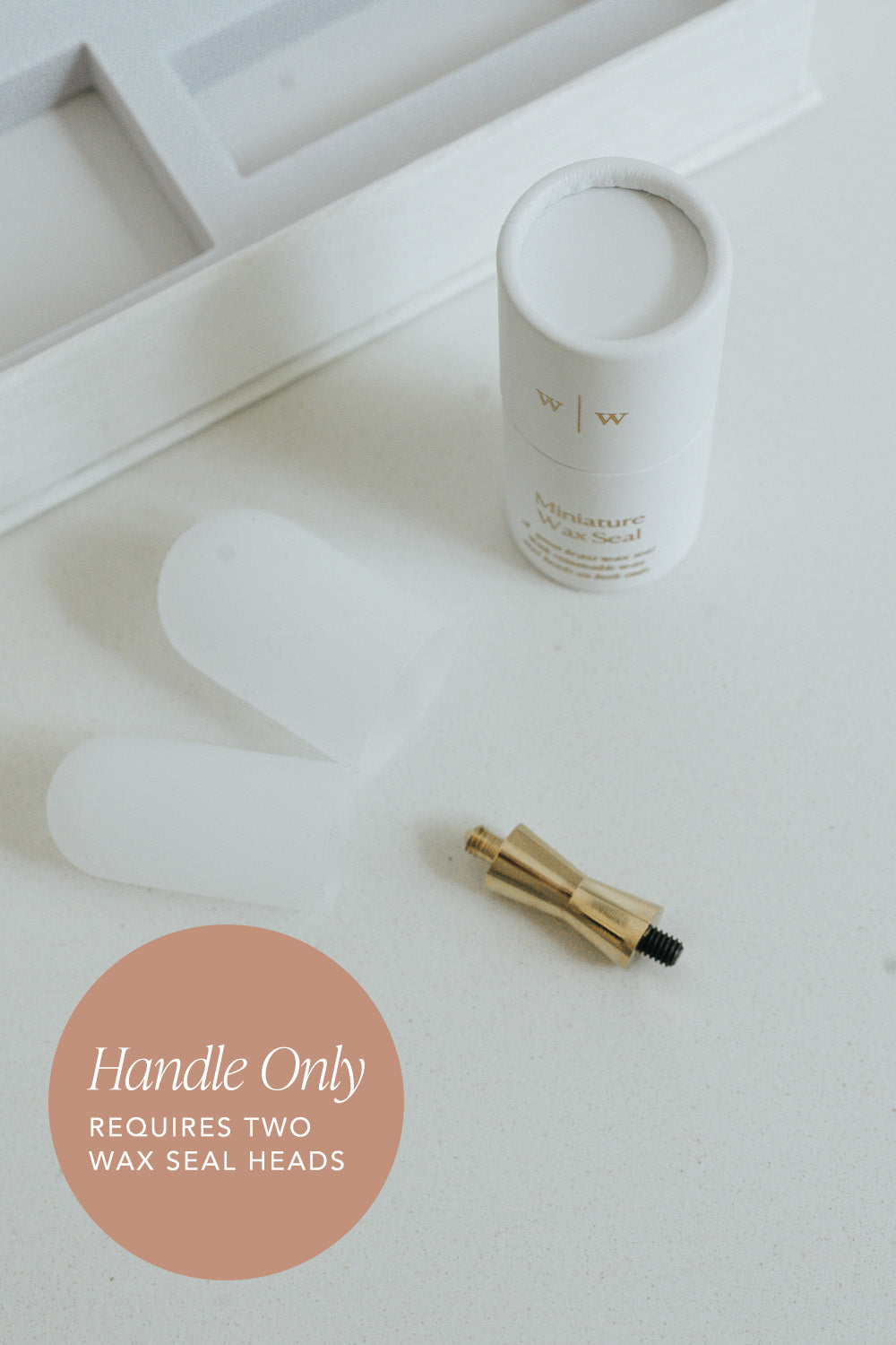 White cylindrical container next to a gold mini wax seal handle on a light surface, with text indicating 'Handle Only' and 'Requires Two Wax Seal Heads'.