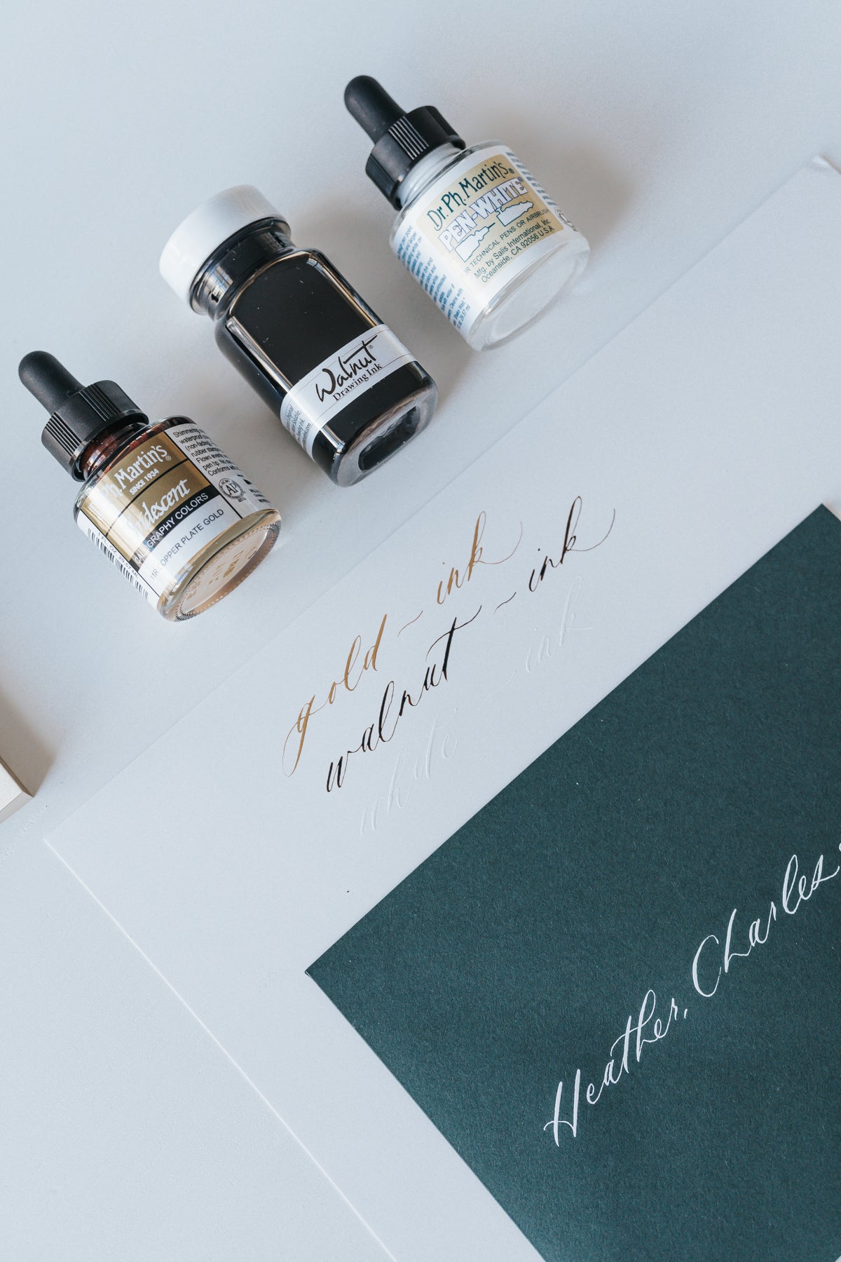 Dr. Ph. Martin's Iridescent, Walnut Drawing Ink, and Pen-White bottles with calligraphy samples on paper
