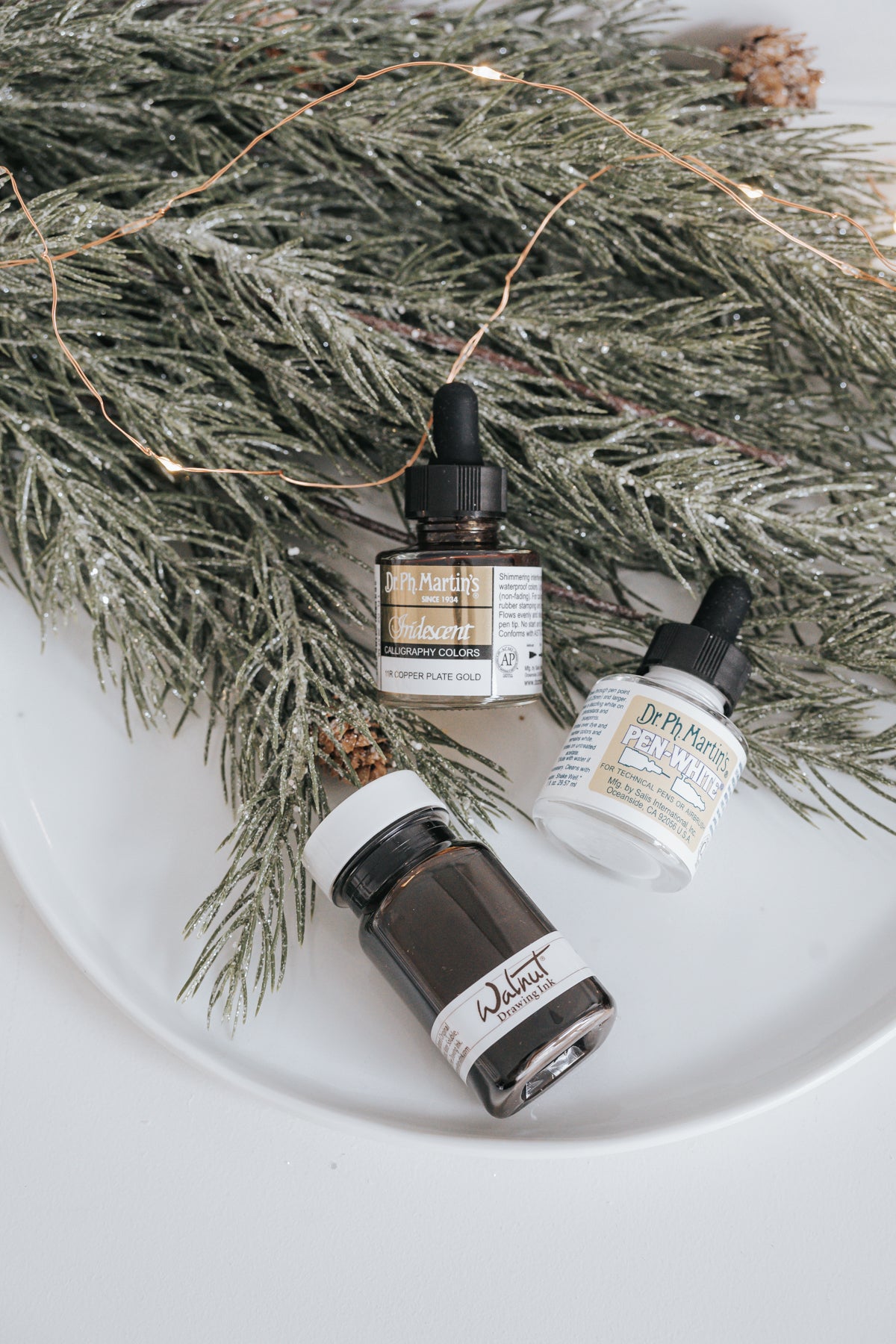 Dr. Ph. Martin's Iridescent, Walnut Drawing Ink, and Pen-White bottles with festive greenery and holiday decor