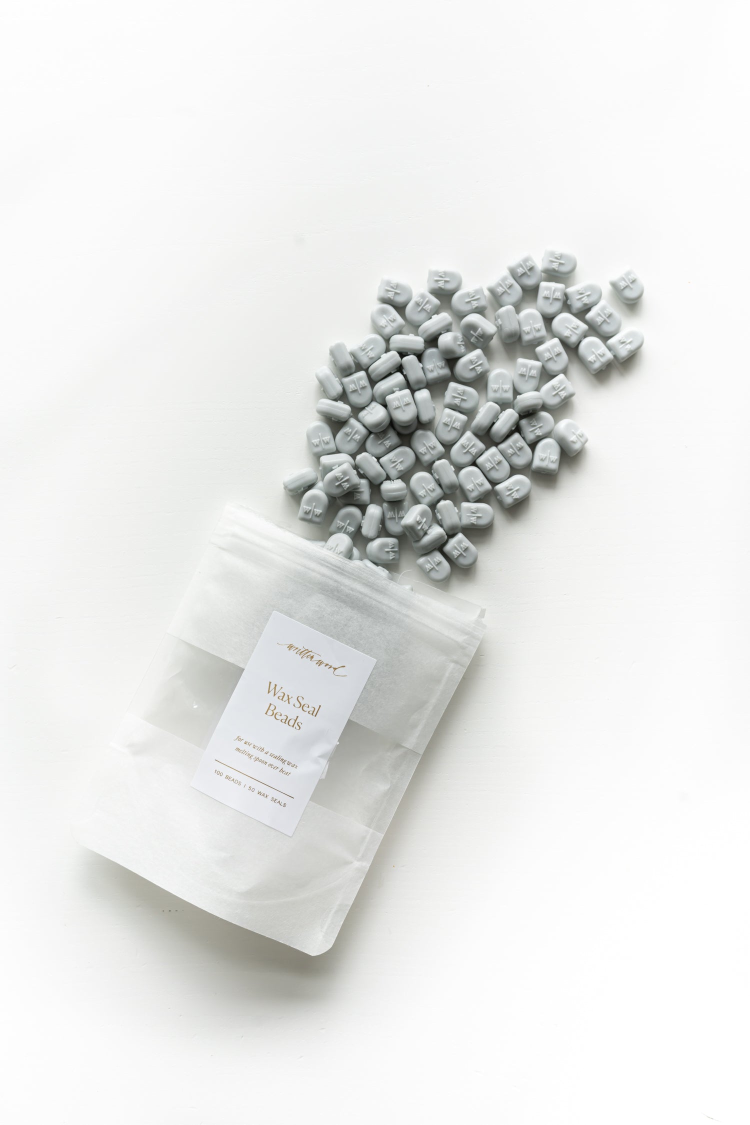 Pale grey wax seal beads spilling from pouch for wax sealing invitations and stationery