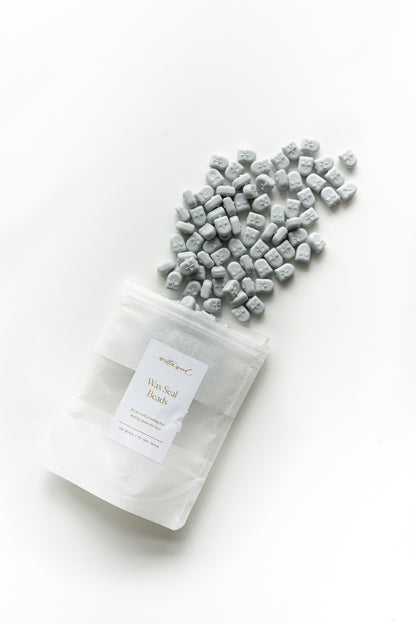Pale grey wax seal beads spilling from pouch for wax sealing invitations and stationery