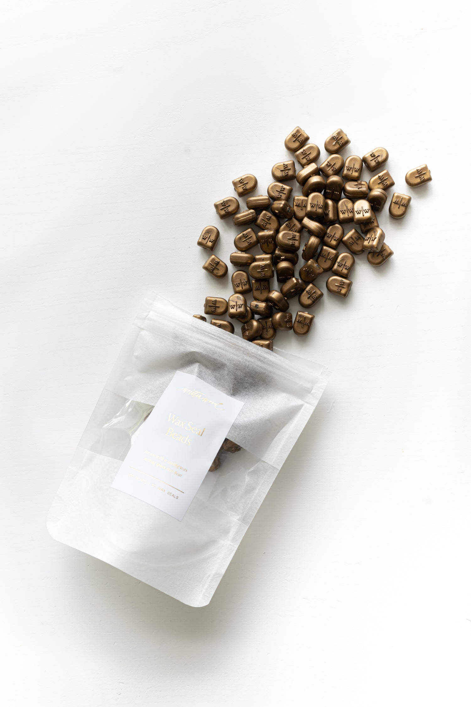 Gold sealing wax beads beside packaging pouch for wax seal crafts and calligraphy