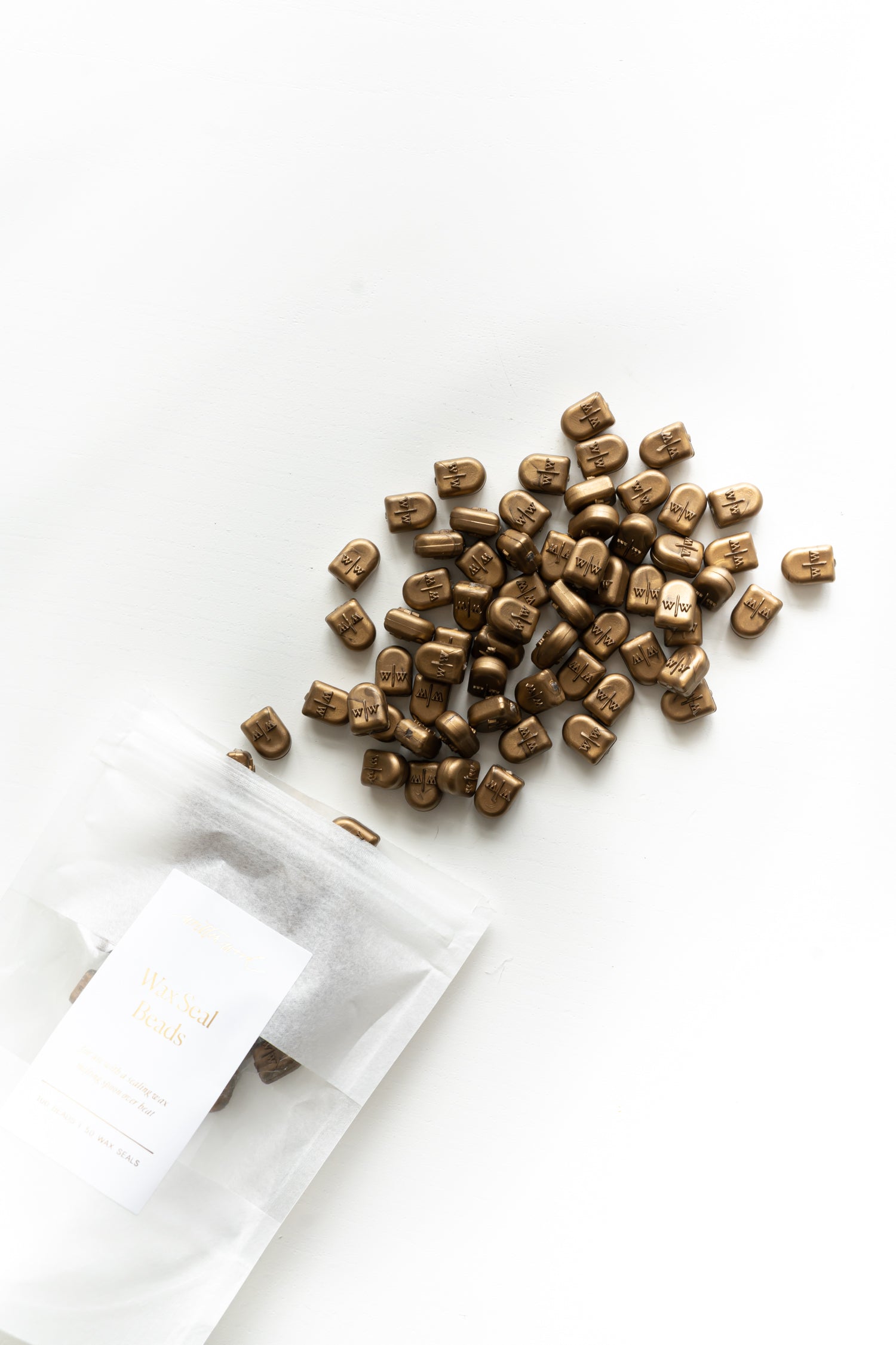 Gold wax seal beads spilling from packaging on white background for wax seal making