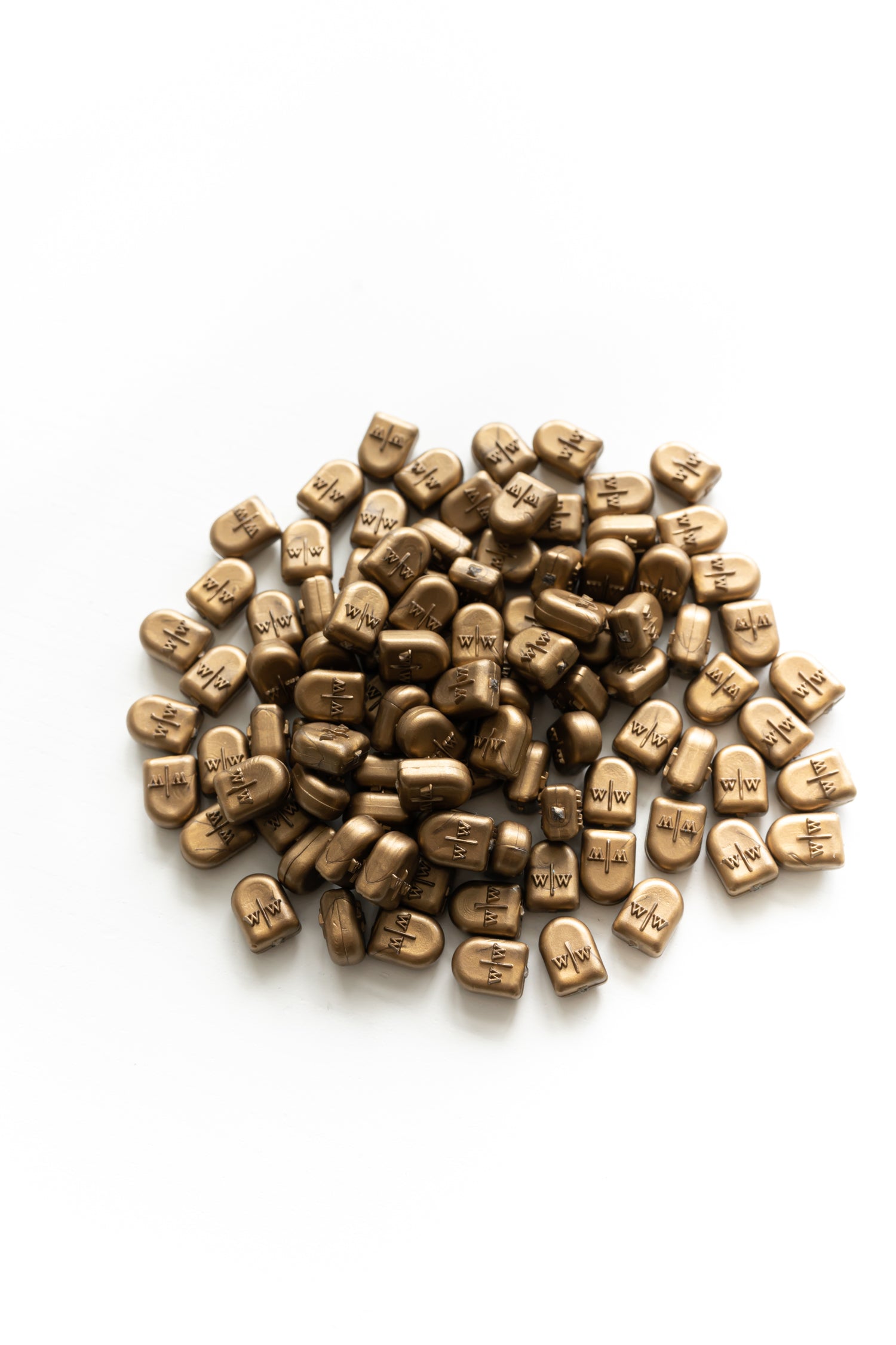 Gold wax seal beads with embossed logo scattered on white background for wax sealing projects