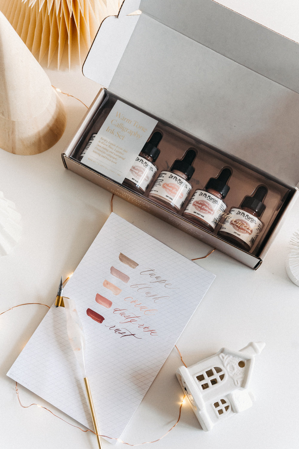 Dr. Ph. Martin's Warm Tone Calligraphy Ink Set with swatches and a dip pen on a desk decorated with festive accents