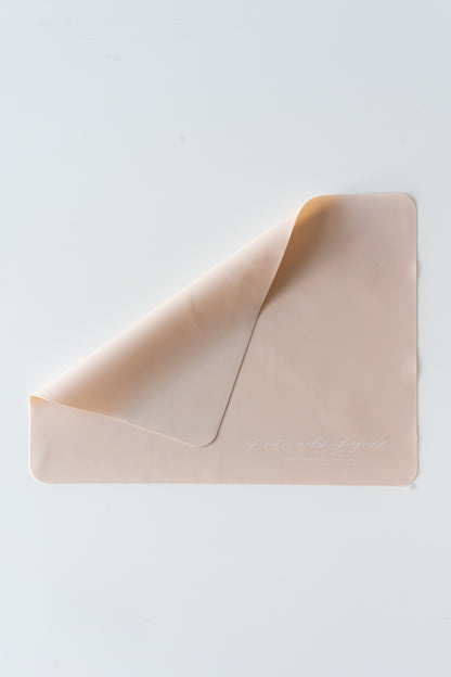 A pink silicone practice mat with the words 'practice makes progress' at the bottom in white