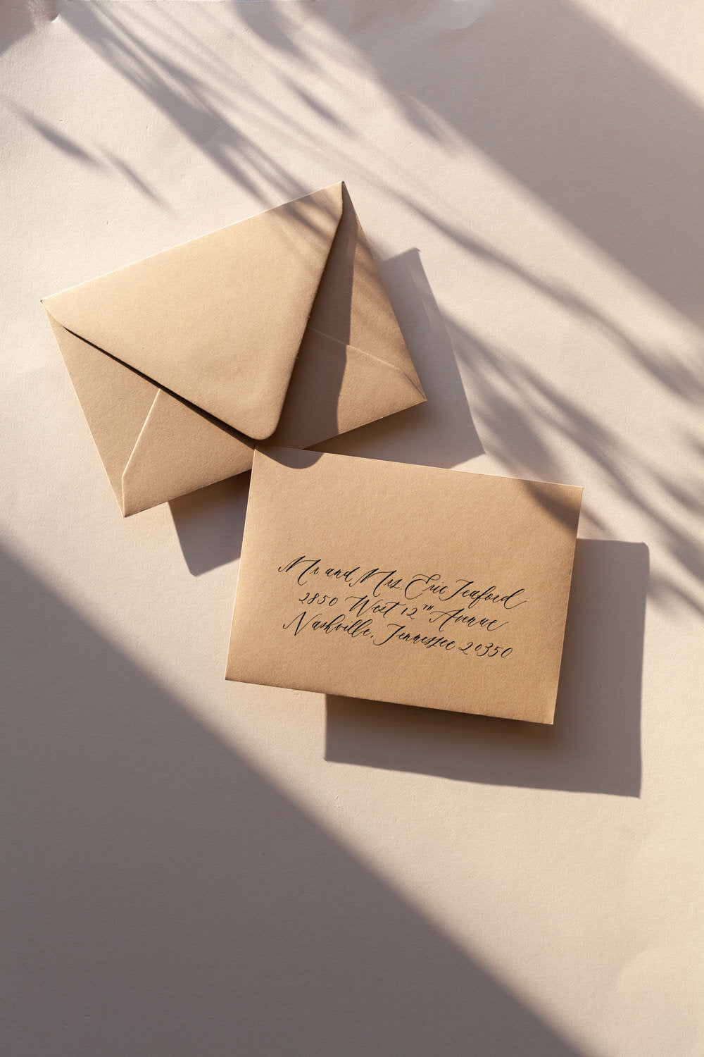 Hand lettered envelope with modern calligraphy address on beige envelope in warm natural light