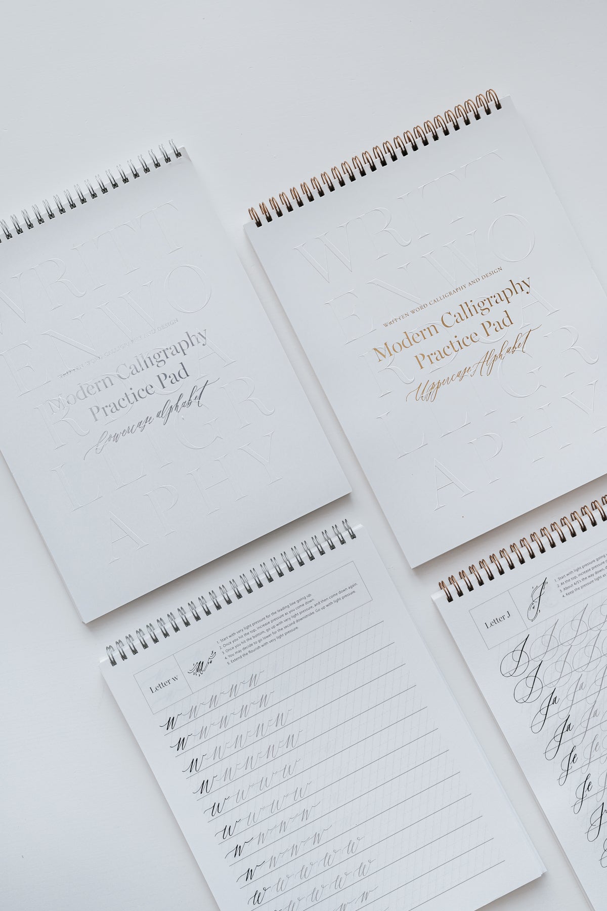 Four modern calligraphy practice pads featuring uppercase and lowercase alphabet exercises, displayed on a white background