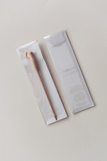 Wooden calligraphy pen with a brass flange displayed in elegant clear packaging on a neutral beige background