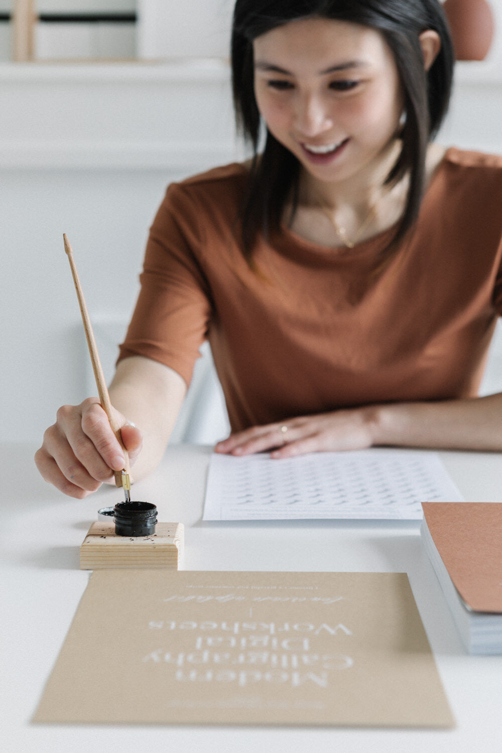 Karla practicing modern calligraphy with dip pen and ink using printable worksheets at desk