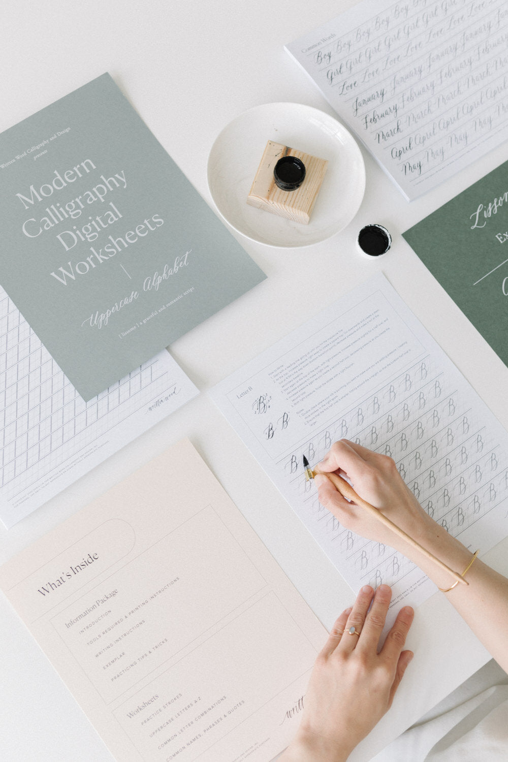 Flat lay of modern calligraphy digital worksheets with ink, pen, and uppercase alphabet practice