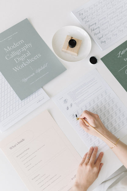 Flat lay of modern calligraphy digital worksheets with ink, pen, and uppercase alphabet practice