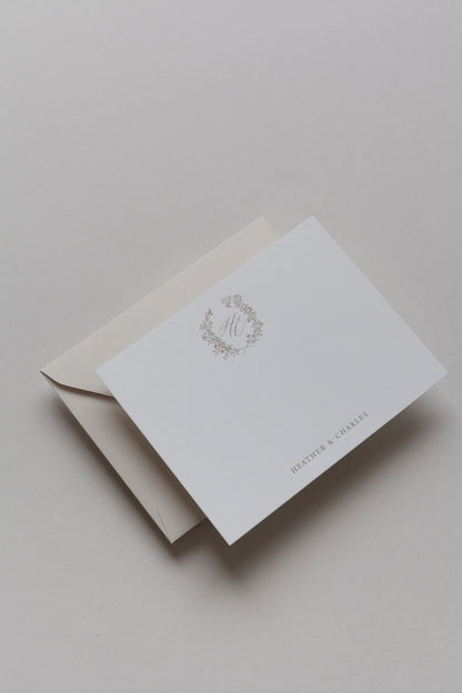 Custom stationery card with gold monogram wreath and envelope in soft neutral tones