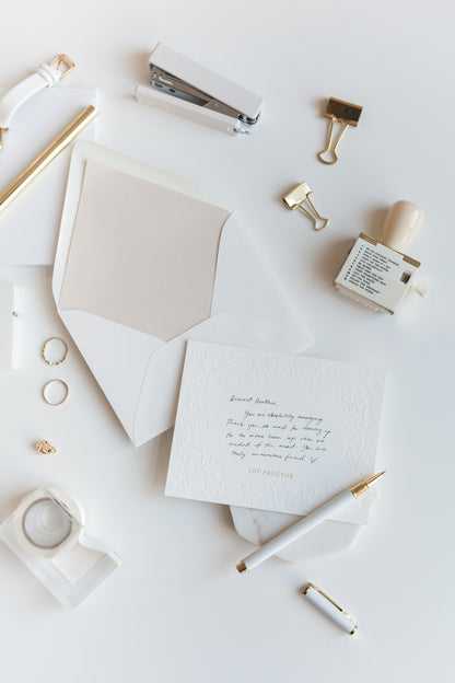 Handwritten note on embossed floral stationery card with gold personalized name