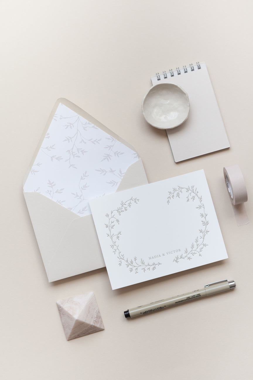 Custom wedding stationery flat lay with floral card, envelope liner, and calligraphy pen