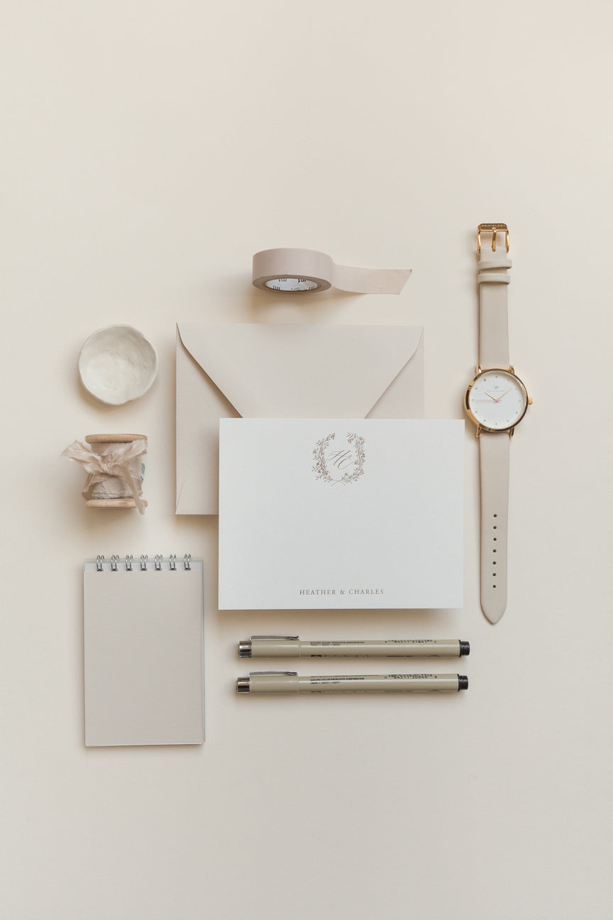 Personalized stationery flat lay with gold monogram, envelope, pens, and neutral desk styling