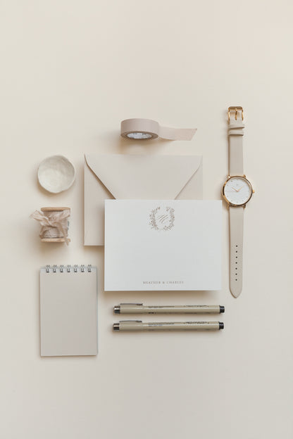 Personalized stationery flat lay with gold monogram, envelope, pens, and neutral desk styling