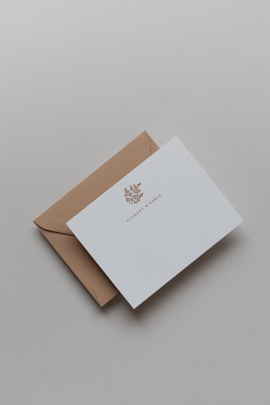Close-up of personalized card with names in serif font and kraft envelope background