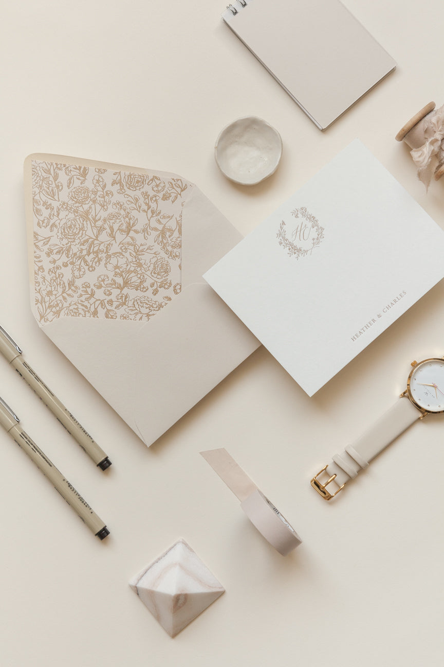 Personalized stationery flat lay with gold monogram, wax seal styling props, and neutral tones